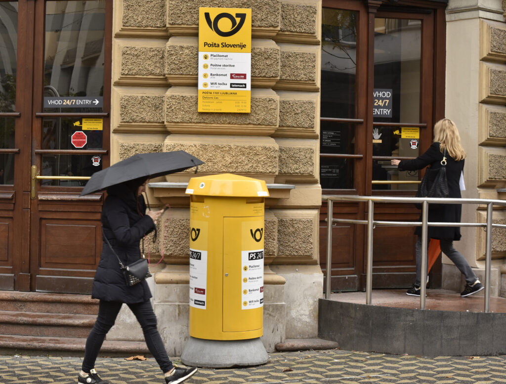 Ženska pred stavbo Pošta Slovenije
